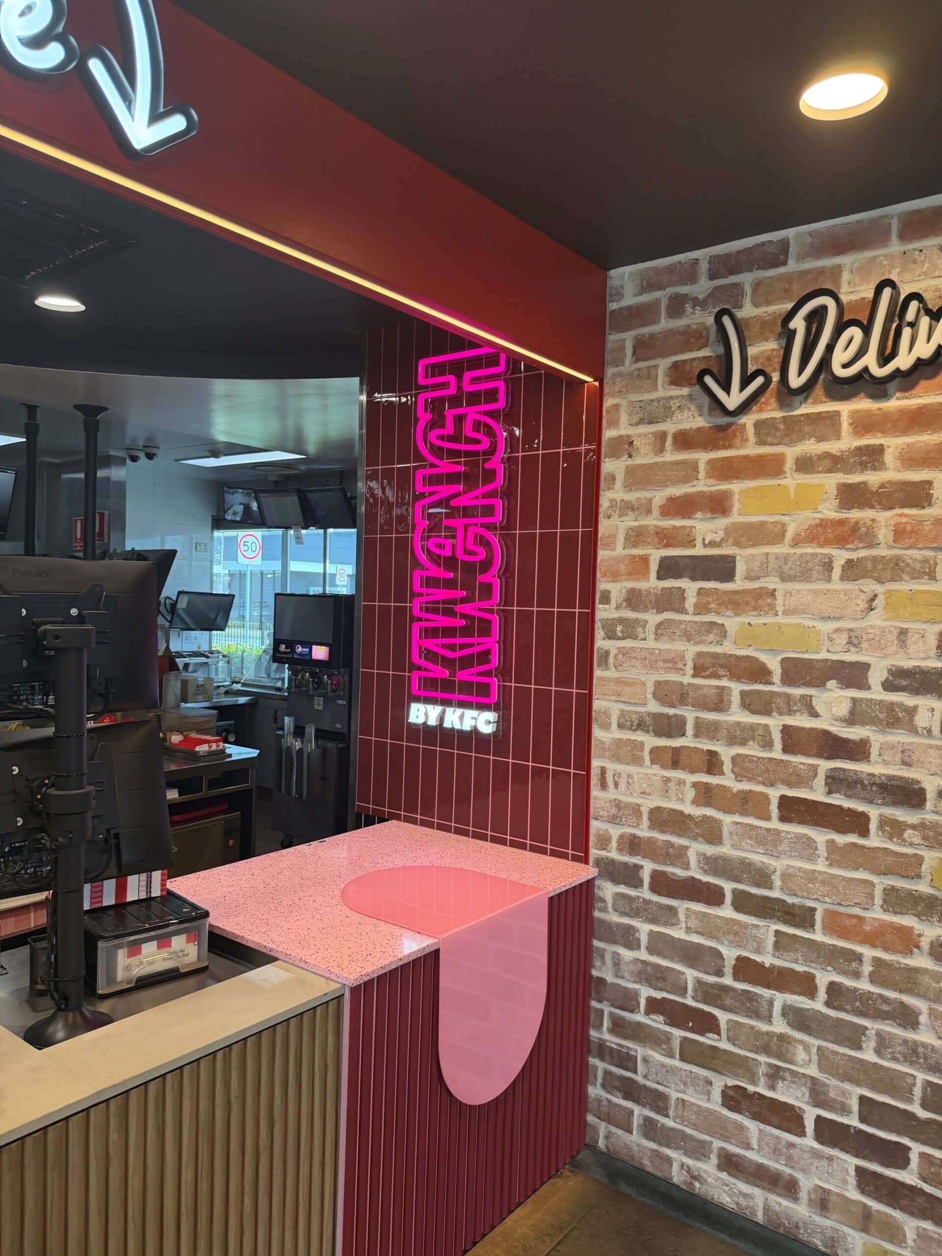 Pink illuminated KWENCH sign beside the KFC counter at Caboolture City, manufactured and installed by Artline Signs.